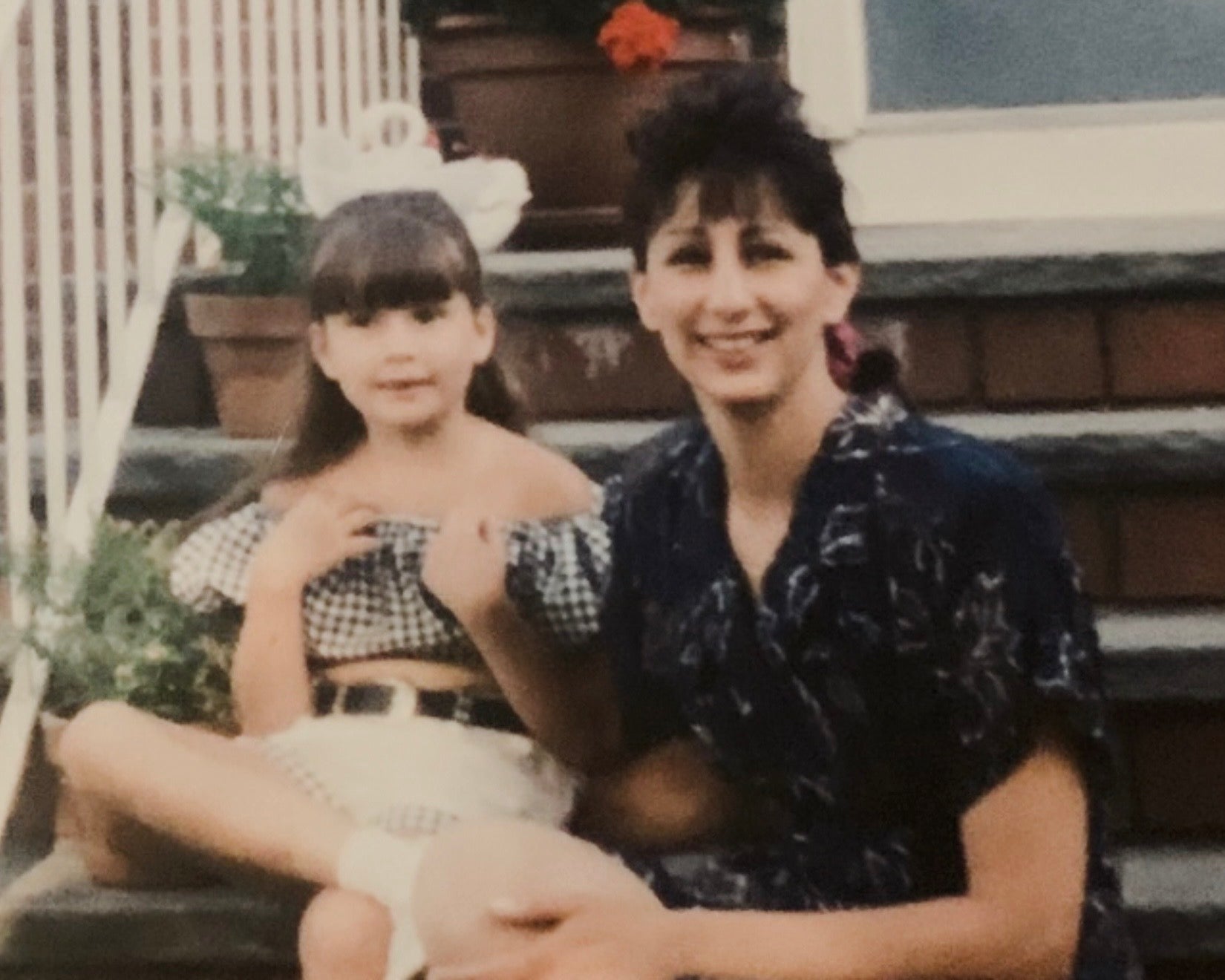 Family photograph of a woman and child seated together on front steps